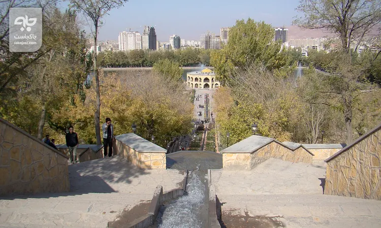 پلکان سنگی و آب‌نمای پله‌ای باغ ائل‌گلی تبریز با درختان زرد و نارنجی پاییزی و عمارت در انتهای مسیر